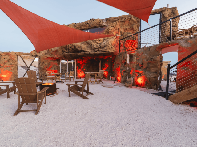 Sandy, Outdoor Lounge with Fire pit and Adirondack chairs. Behind the Basalt Wall Panel Covers the Facade of a home