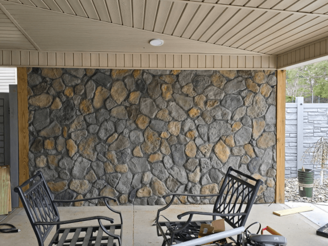 Basement Walkout Patio With Two Black Chairs. Against the Far, The Crazystone Panel Is Mounted, Covering the Wall