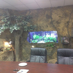 A Meeting Room. Behind, The Crystal Rock Panel Covers the Wall, with a cutout for a Large Fish Tank. 