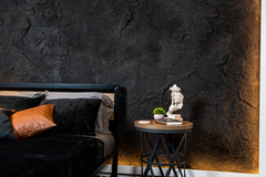 A Bed With Black Sheets and a Bedside Table. Behind, The Dragon Stone Panel Covers the Wall