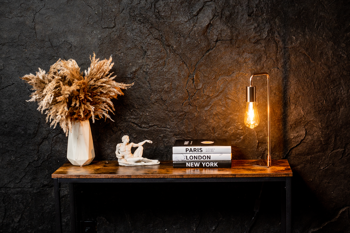 A Black Metal Table with a wooden top. The Wall behind is decorated with the Dragonstone Panel