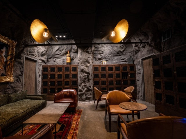 Large Basement Lounge, The Malawi Wall Panel Covering Back and Side Walls, with large lights hanging above on dark ceiling 
