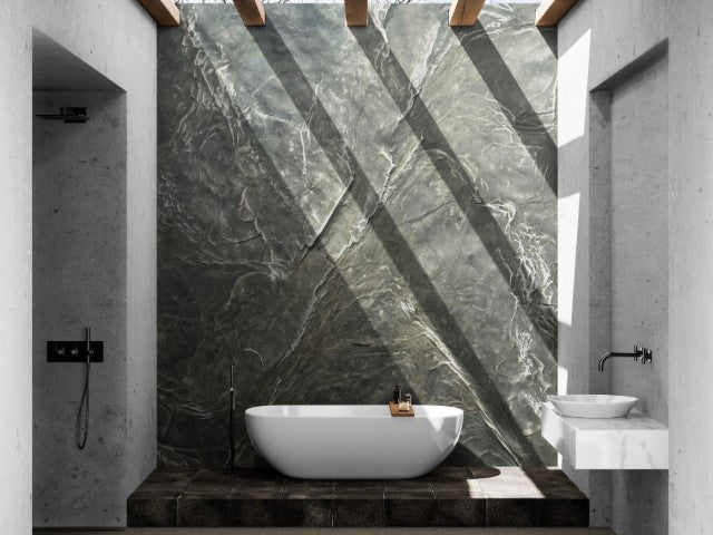A Modern Bathtub sitting on a stone pedestal. Behind, the Slate Wall Panel Covers the Wall