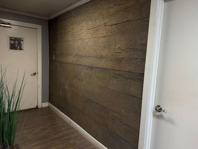 A Dark Floored Hallway With Two White Doors. On The Far Wall, The Woodland Panel is mounted over the drywall